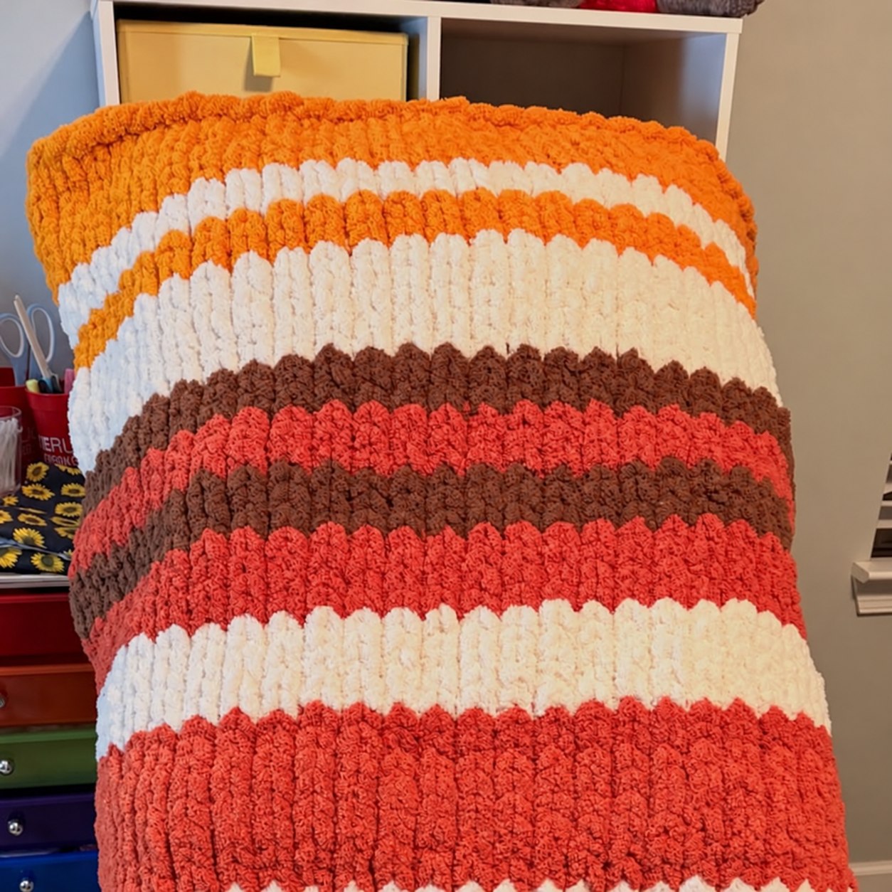 Chunky knit blanket with coral, cream, brown, and orange stripes